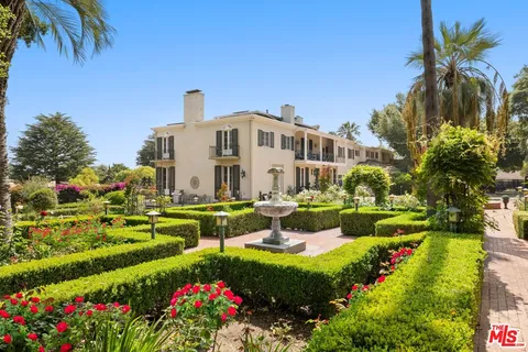 a front view of a house with a big yard and potted plants