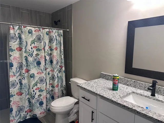 a bathroom with a granite countertop sink a toilet and a mirror