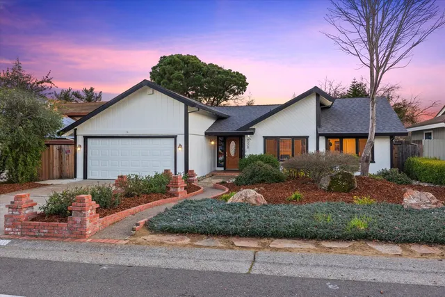 a front view of a house with a yard and potted plants