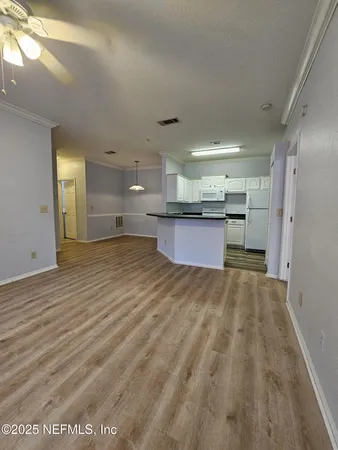 a view of kitchen and empty room with wooden floor