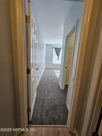 a view of a hallway with wooden floor and a livingroom