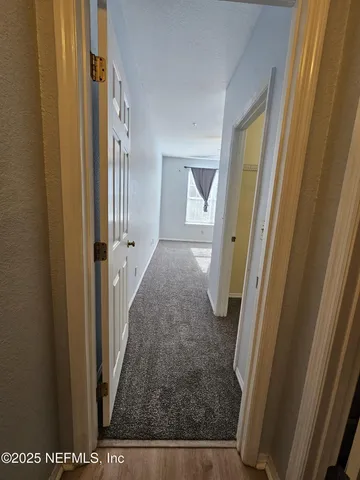 a view of a hallway with wooden floor and a livingroom