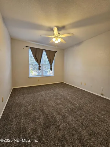 an empty room with a window and a ceiling fan
