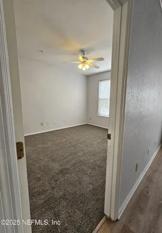 an empty room with windows and chandelier fan