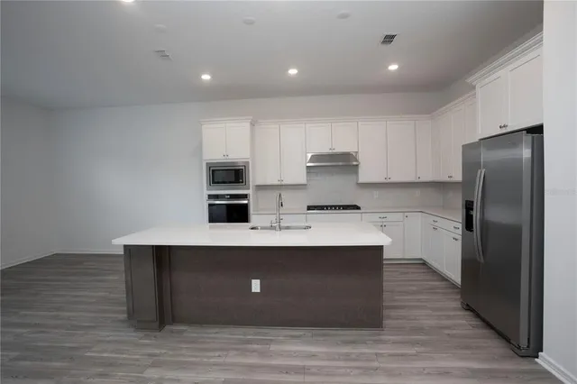 a view of a kitchen with wooden floor and electronic appliances
