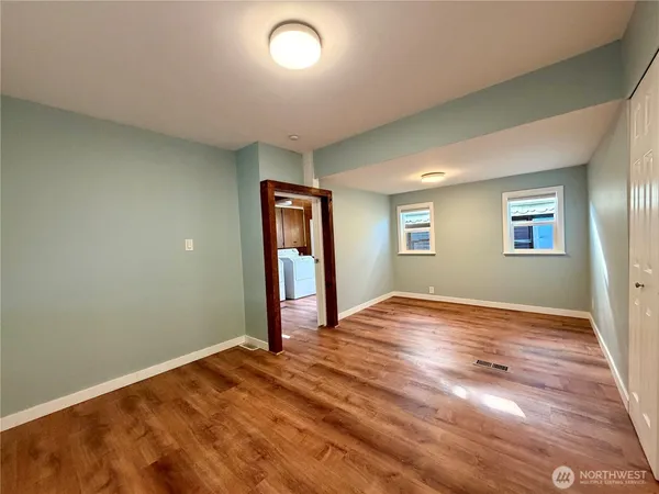 a view of empty room with window and wooden floor