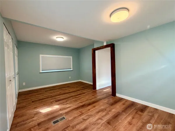 an empty room with wooden floor and windows