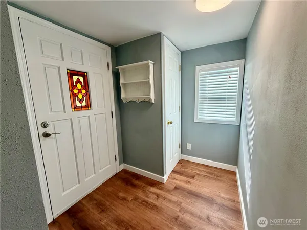 a view of an empty room with wooden floor and a window