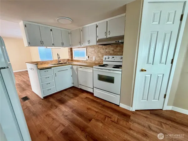 a kitchen with granite countertop a sink a stove and cabinets