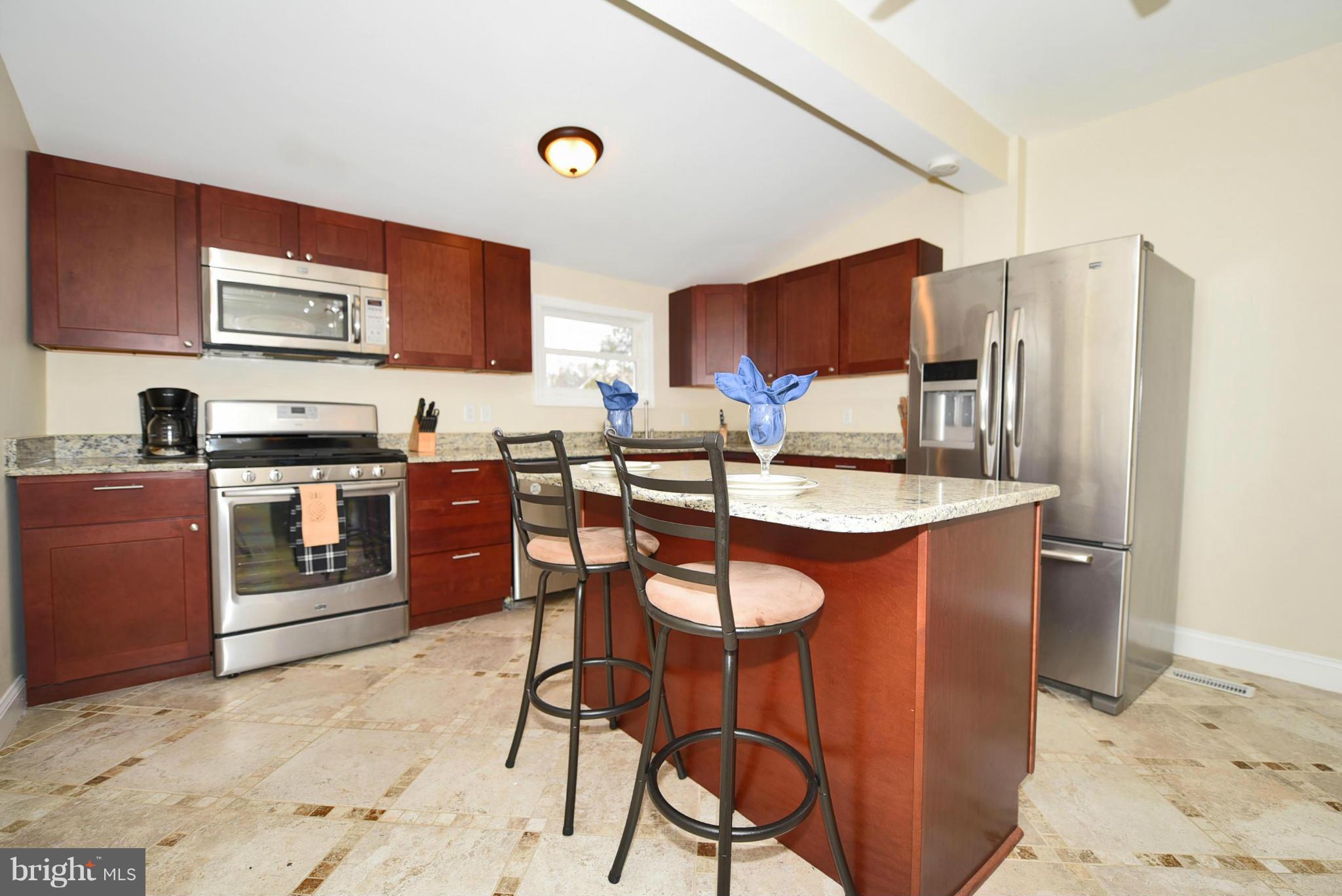 710 Elmwood Road Baltimore, MD 21206 - Photo 7 of 30 a kitchen with stainless steel appliances kitchen island granite countertop a sink a stove a refrigerator cabinets and chairs