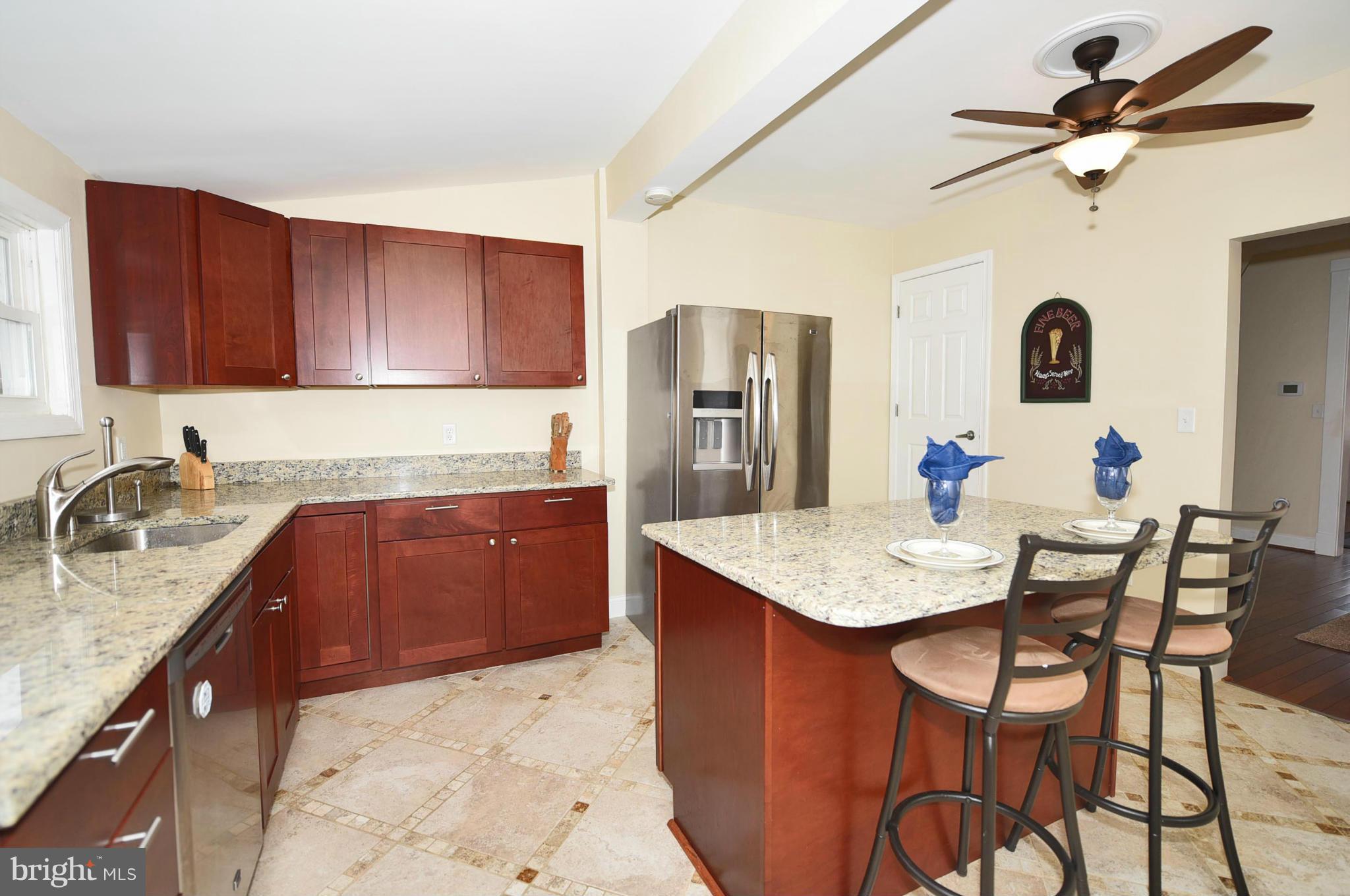 710 Elmwood Road Baltimore, MD 21206 - Photo 8 of 30 a kitchen with stainless steel appliances kitchen island granite countertop a dining table chairs and a refrigerator