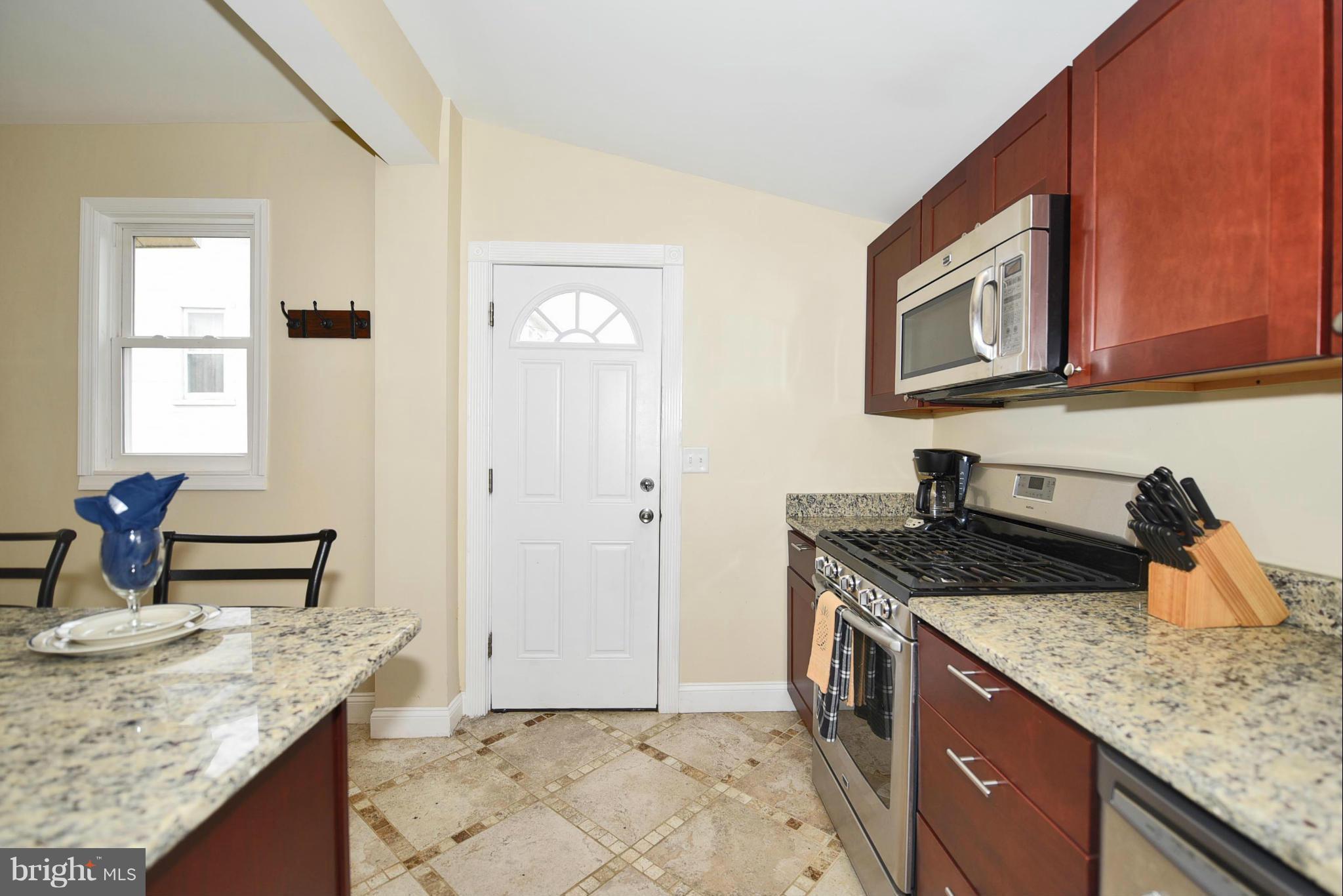 710 Elmwood Road Baltimore, MD 21206 - Photo 10 of 30 a kitchen with granite countertop a sink a stove and a wooden cabinets