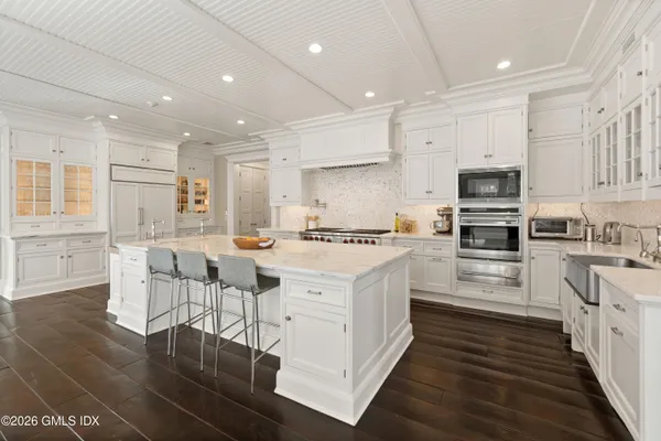 a kitchen with stainless steel appliances kitchen island granite countertop a stove top oven a sink a dining table and chairs with wooden floor