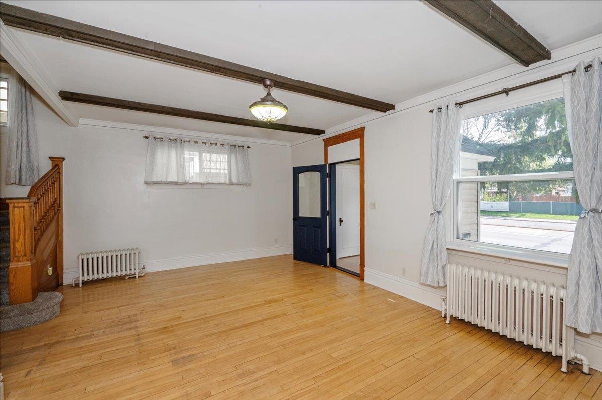 2127 Tower Avenue Superior, WI 54880 - Photo 13 of 39 Empty room featuring radiator heating unit, beamed ceiling, plenty of natural light, and light wood finished floors