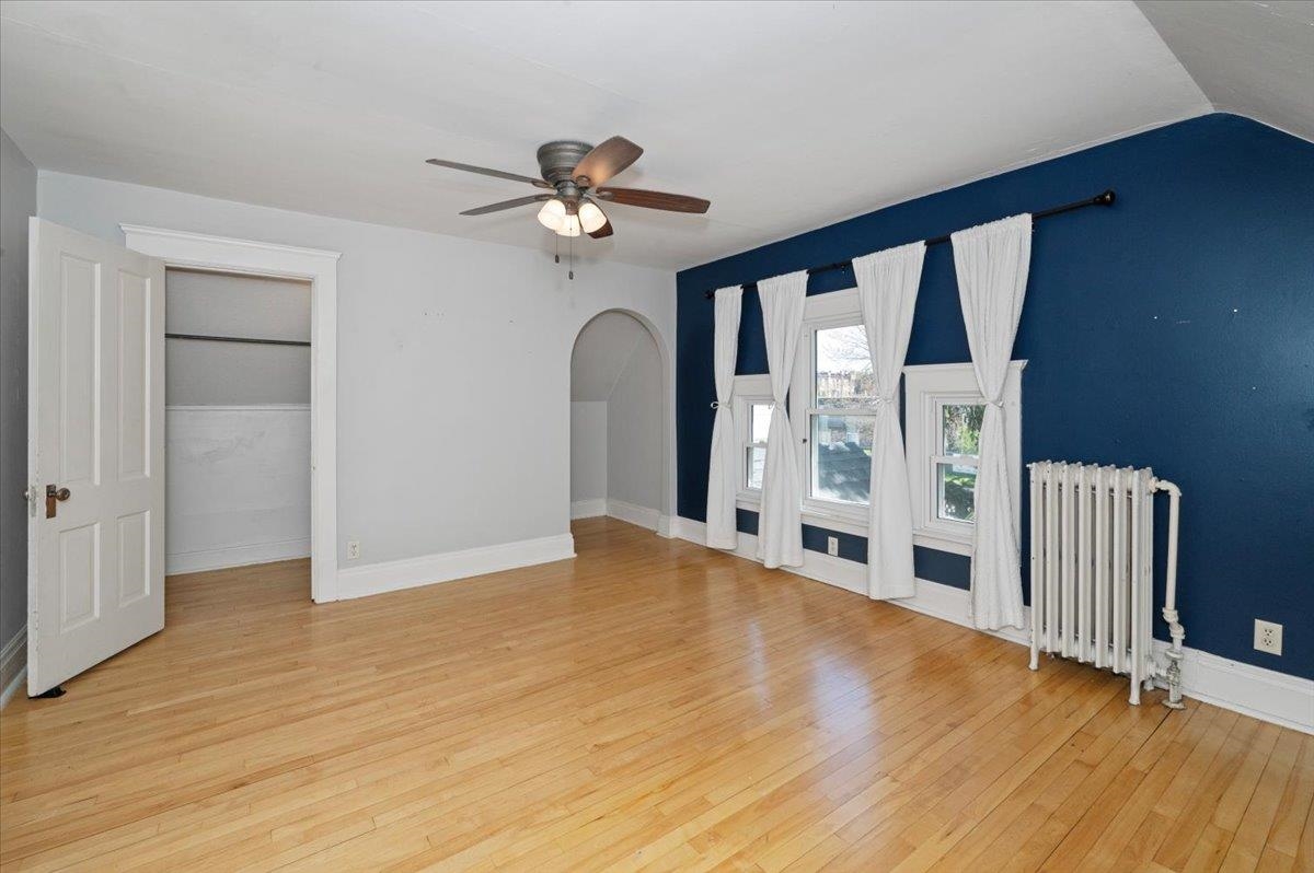 2127 Tower Avenue Superior, WI 54880 - Photo 23 of 39 Additional living space featuring radiator, light wood-style floors, ceiling fan, arched walkways, and baseboards