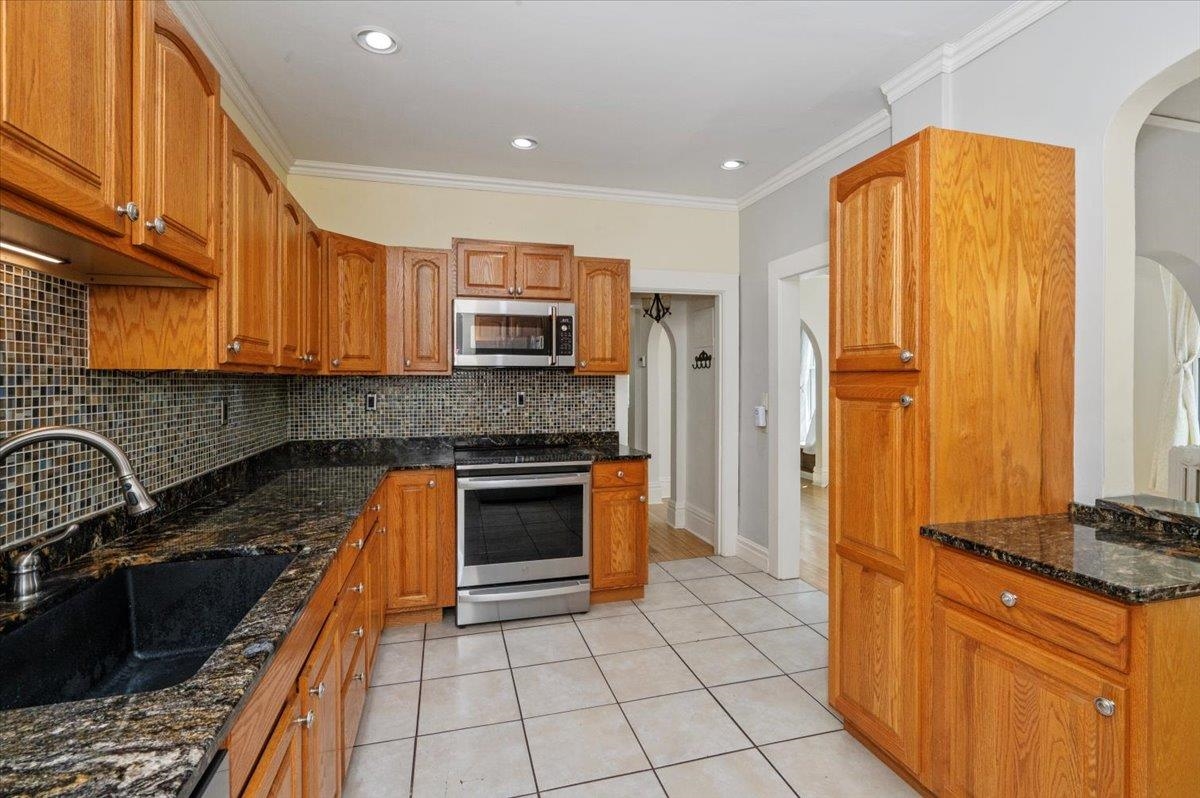 2127 Tower Avenue Superior, WI 54880 - Photo 3 of 39 Kitchen featuring stainless steel appliances, a sink, arched walkways, light tile patterned floors, and backsplash