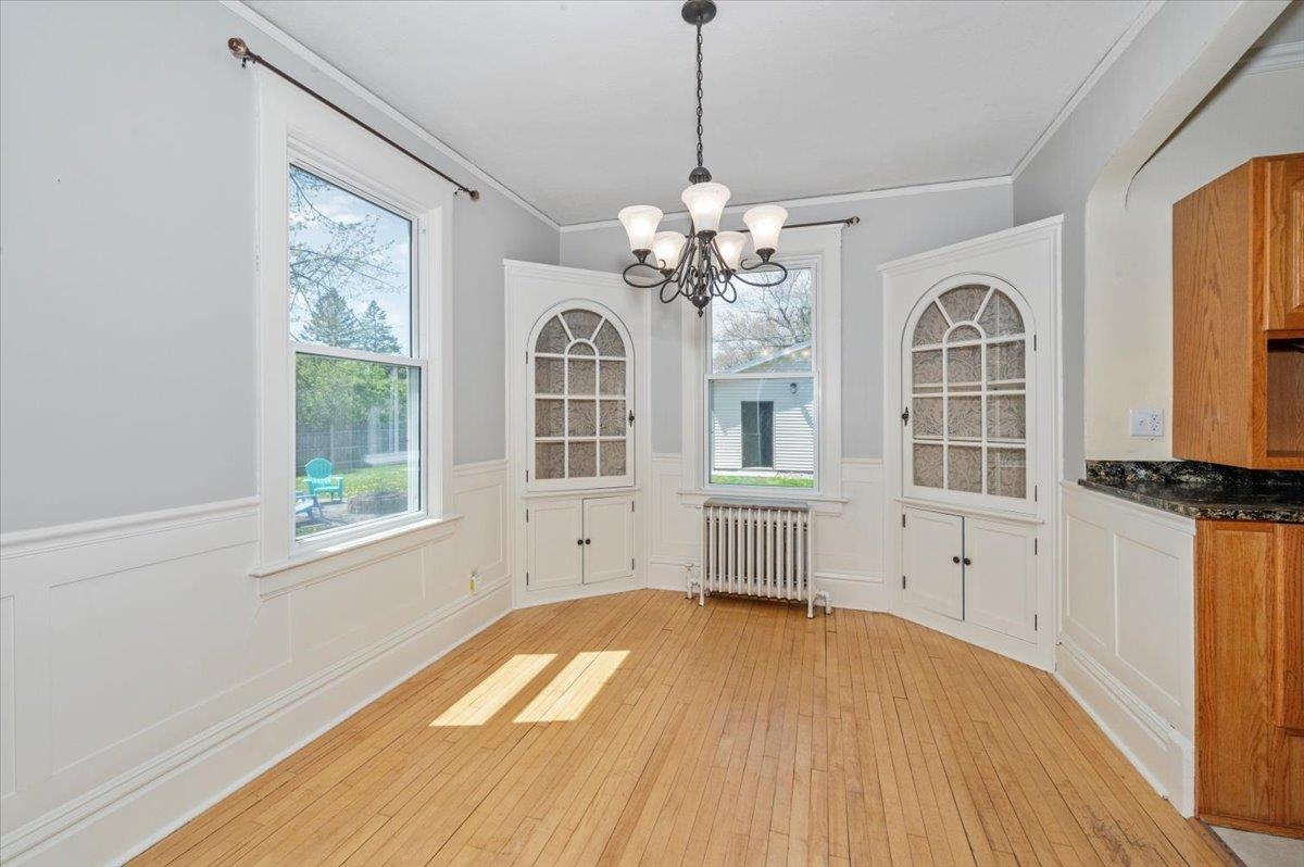 2127 Tower Avenue Superior, WI 54880 - Photo 8 of 39 Unfurnished dining area with radiator heating unit, a wainscoted wall, a chandelier, light wood finished floors, and ornamental molding