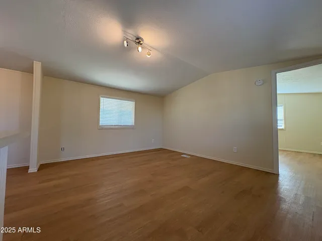an empty room with wooden floor fan and windows