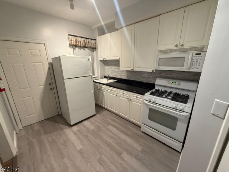751 East 25th Street, Unit 2 Paterson, NJ 07504 - Photo 5 of 8 a kitchen with a refrigerator stove and white cabinets