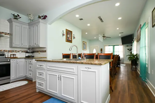 a kitchen with granite countertop a sink cabinets and wooden floor