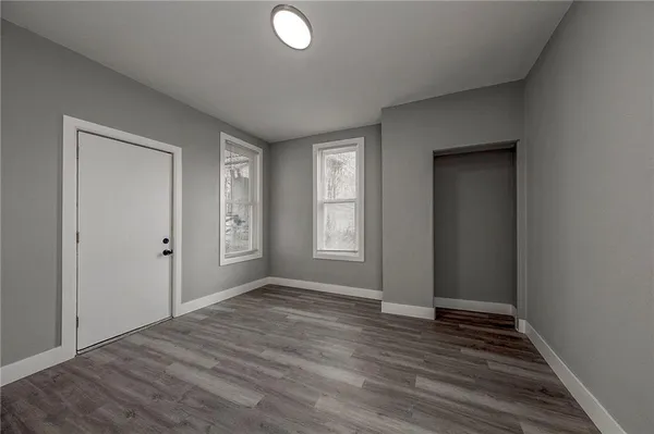 a view of an empty room with wooden floor and a window