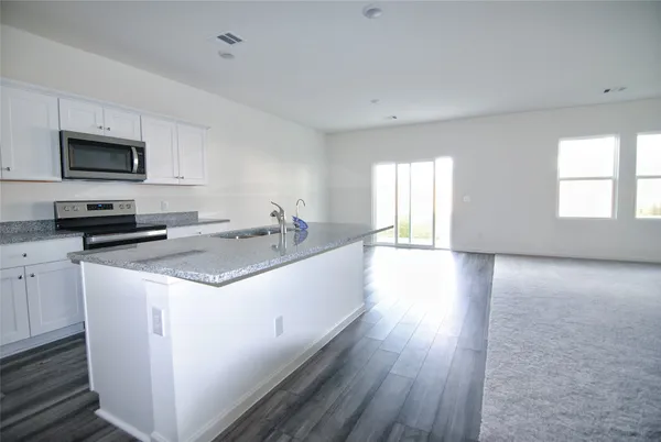 a kitchen with stainless steel appliances granite countertop a sink a microwave cabinets and a wooden floor