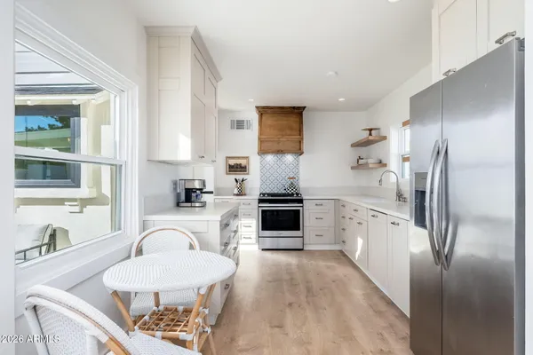 a large kitchen with stainless steel appliances a refrigerator a sink a stove a table and chairs