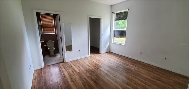 a view of an empty room with wooden floor and closet