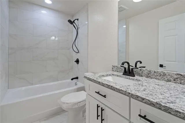 a bathroom with a granite countertop sink a toilet and shower