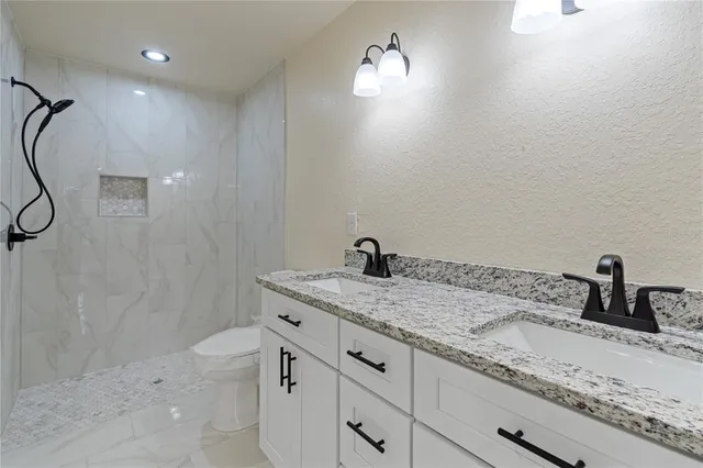 a bathroom with a granite countertop sink a toilet and mirror