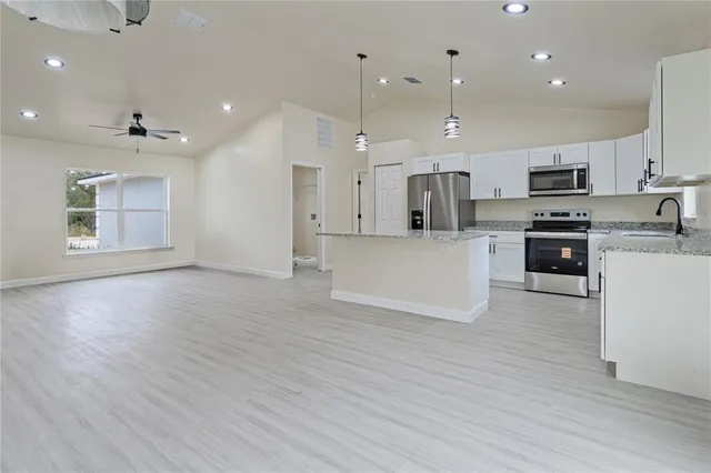 a large kitchen with stainless steel appliances kitchen island a large counter top and a wooden floors