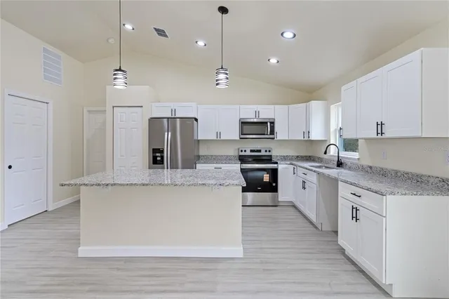 a large kitchen with cabinets wooden floor and stainless steel appliances