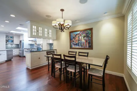 a dining room with wooden floor a chandelier a wooden table and chairs