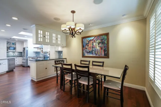 a dining room with wooden floor a chandelier a wooden table and chairs