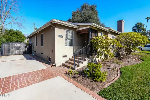 a view of a house with a yard and potted plants