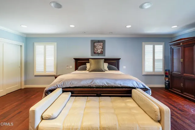 a spacious bedroom with a bed and wooden floor