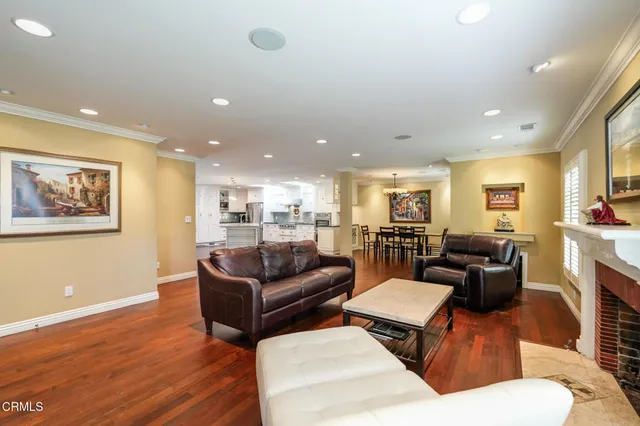 a living room with furniture kitchen view and a wooden floor