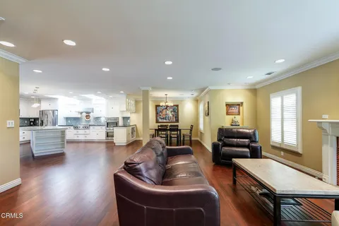 a living room with furniture kitchen view and a wooden floor