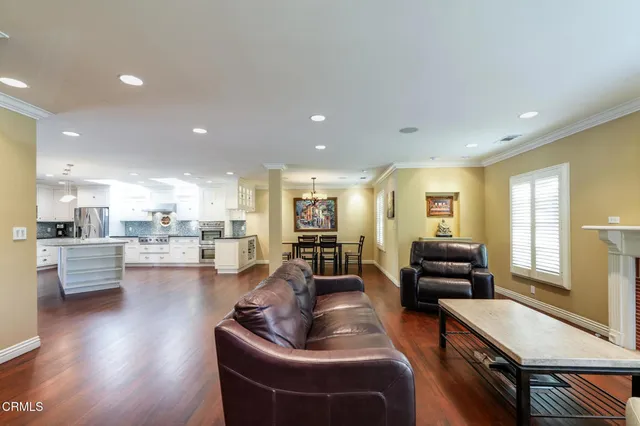 a living room with furniture kitchen view and a wooden floor