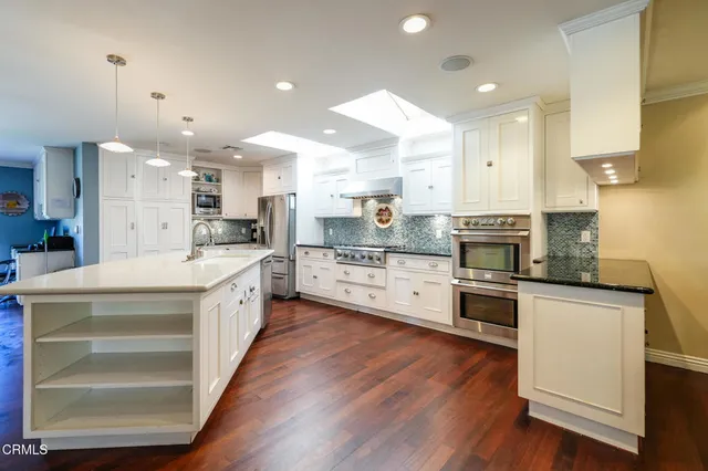 a large kitchen with stainless steel appliances kitchen island a large counter top and a stove top oven