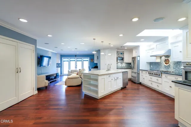 a large white kitchen with a large counter top appliances and cabinets