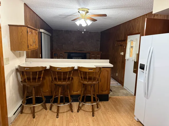 a dining room with stainless steel appliances kitchen island granite countertop a refrigerator a stove a sink with island chairs and wooden floor