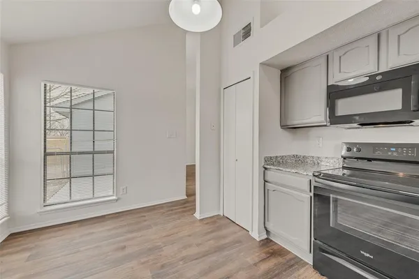 a kitchen with granite countertop a stove top oven a sink and dishwasher with white cabinets