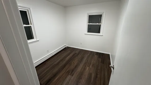 an empty room with wooden floor and entrance