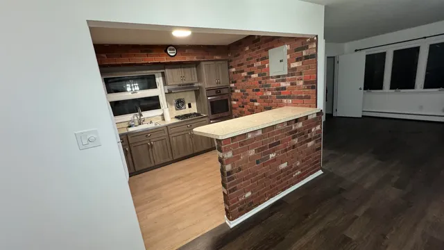 a kitchen with stainless steel appliances wooden floor and a refrigerator
