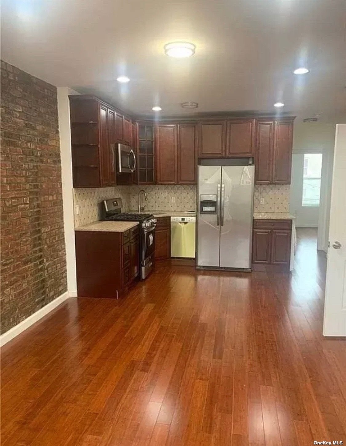 a kitchen with stainless steel appliances granite countertop a refrigerator a sink dishwasher a stove and a wooden floors