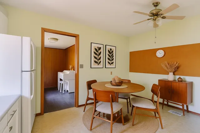 a dining room with furniture and a chandelier fan