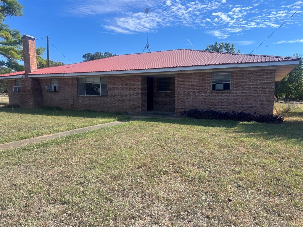 203 Washington Avenue Strawn, TX 76475 - Photo 1 of 20 Back of house with brick siding, a chimney, a lawn, and a metal roof