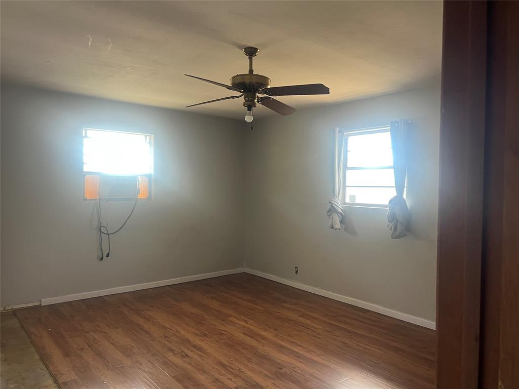 203 Washington Avenue Strawn, TX 76475 - Photo 12 of 20 Unfurnished room featuring dark wood-style flooring and ceiling fan