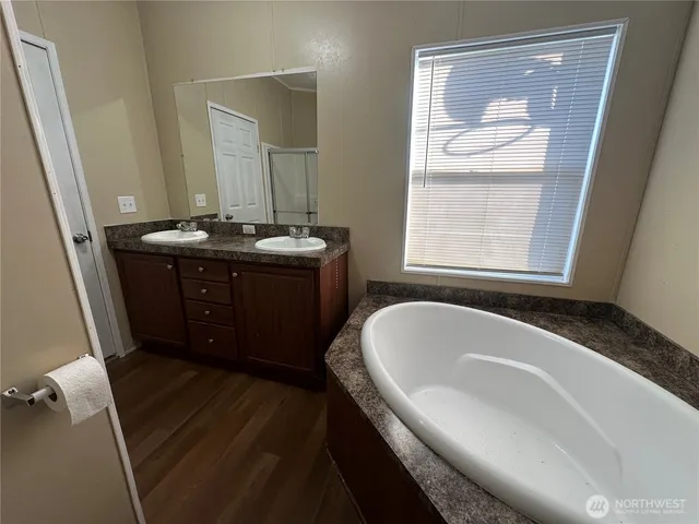 a spacious bathroom with a granite countertop sink a mirror and a bathtub